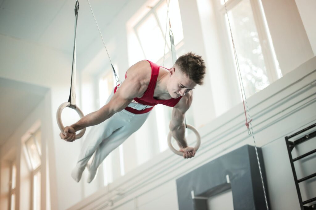 photo of male gymnast practicing on gymnastic rings